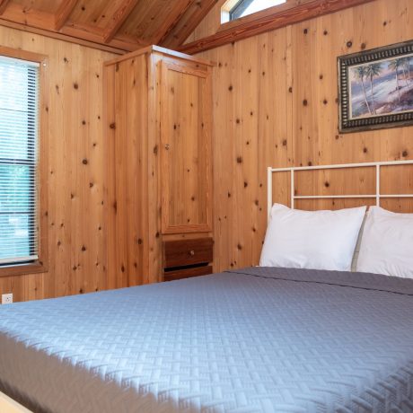 Bedroom with queen size bed and windows in a wooden home