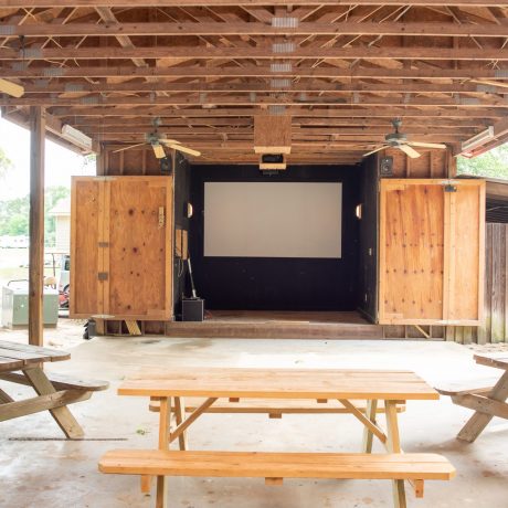 Outdoor recreation with projector screen stage and awning structure