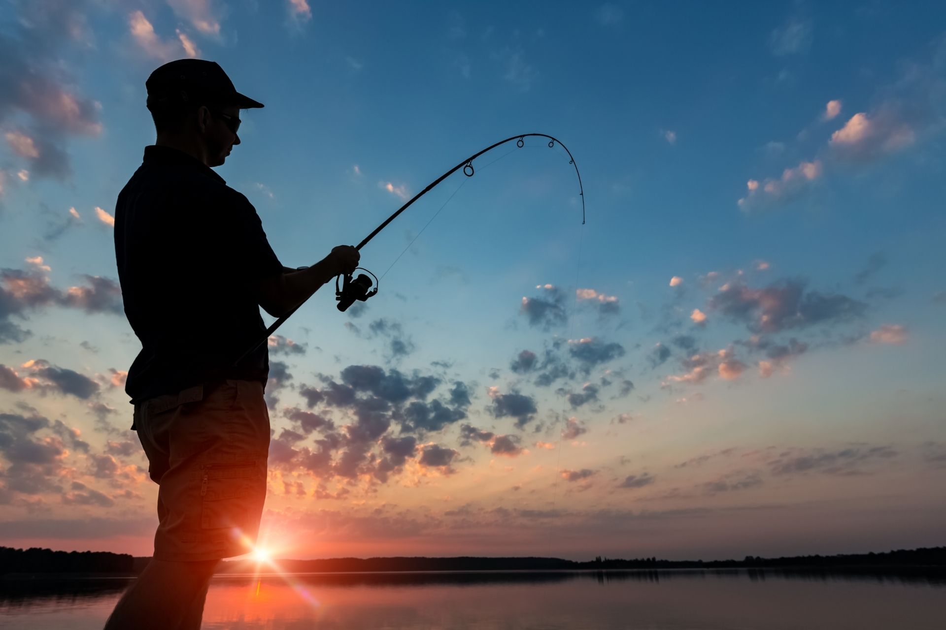 A man's silhouette fishing in the sunset